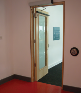 Automatinės durys ir prie sienos pritvirtintas durų atdarymo mygtukas